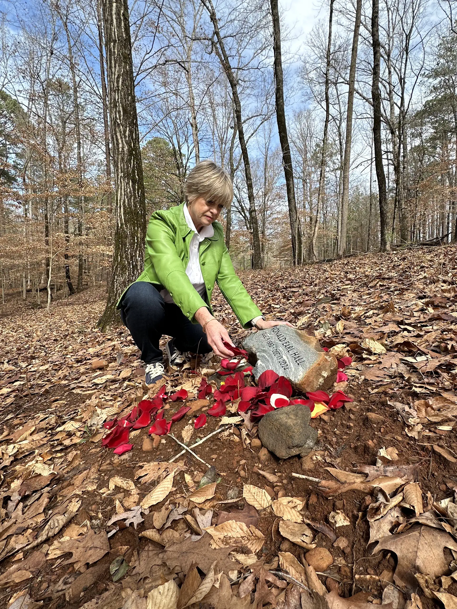 Darlene Hall places rose petals on her husband Ronnies tribute stone at Whispering Hills