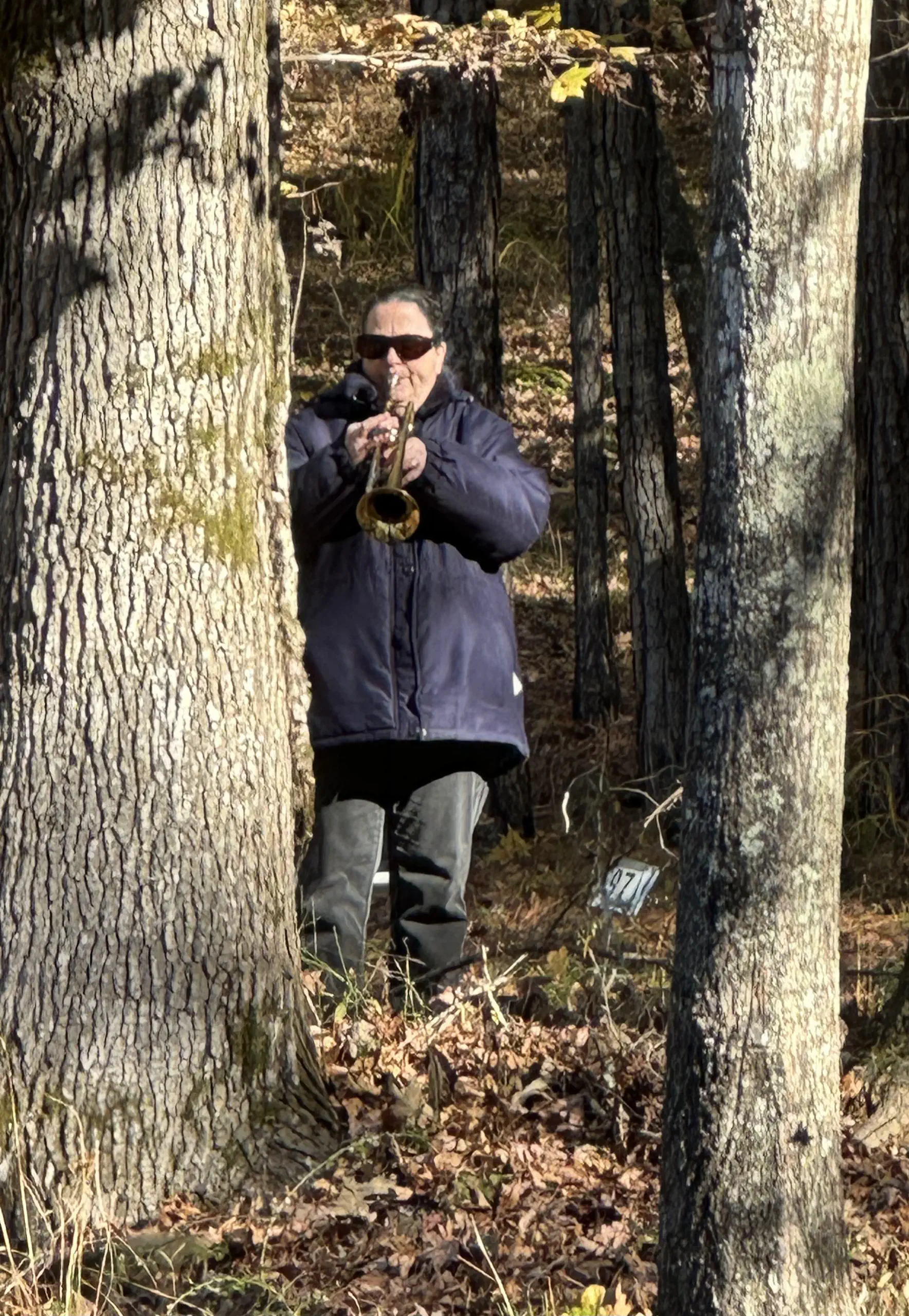 Tucked in the trees, bugler LaZette closes the Veterans Day ceremony with Taps